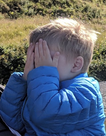 Boy with hands over his eyes